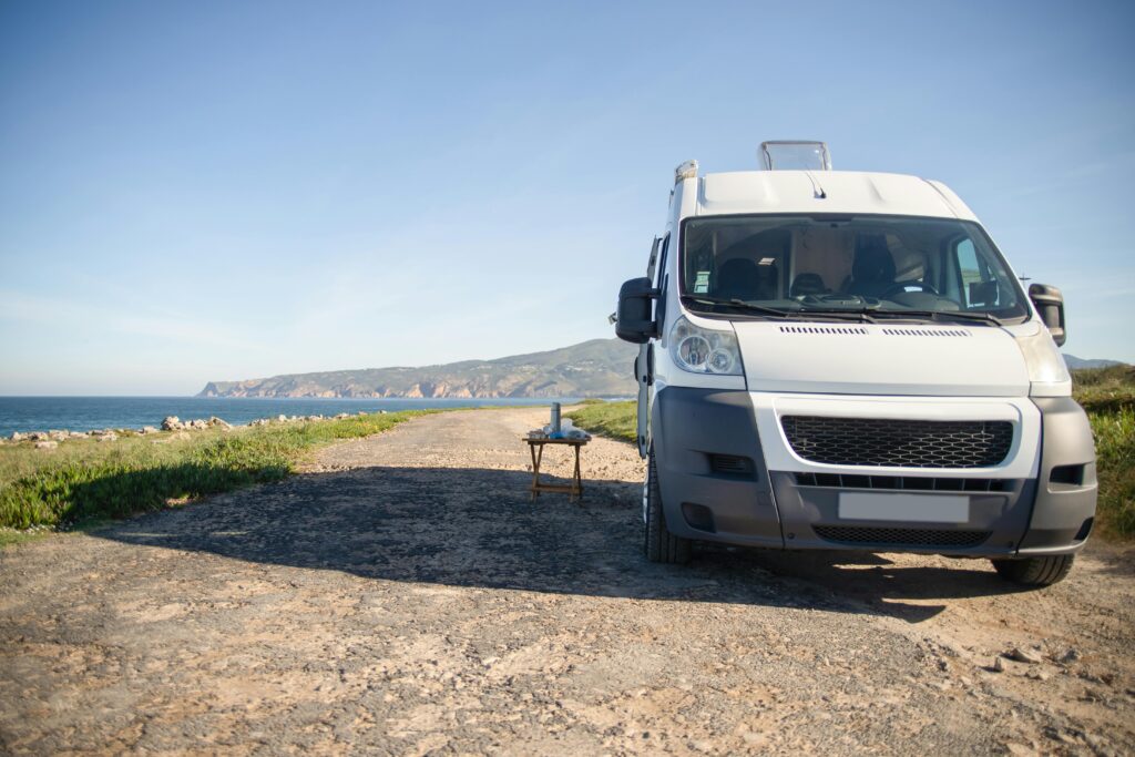 pexels-photo-7476890-7476890 Camper van parked on a coastal road with ocean view in Portugal, perfect for summer travel.